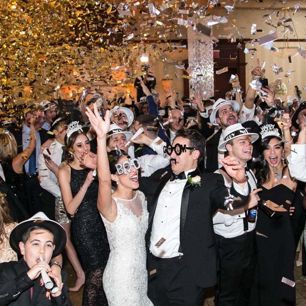 Bride and Groom dancing with the crowd and gold confetti falling
