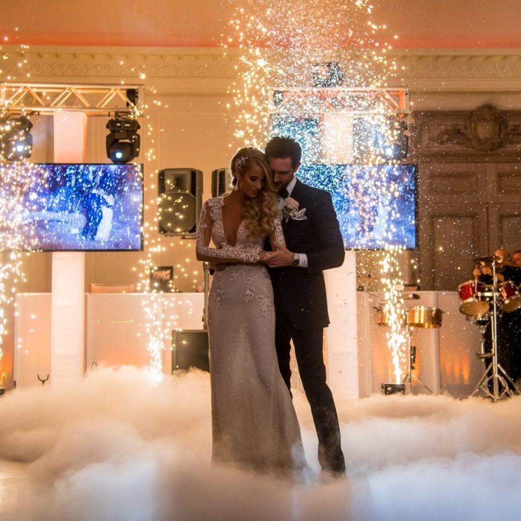 Bride and Groom Dancing on clouds in front of sparks and video displays