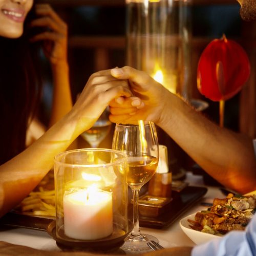 Romantic couple holding hands together over candlelight