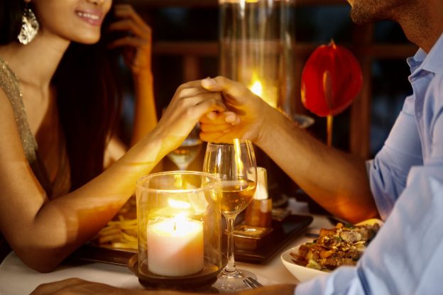 Romantic couple holding hands together over candlelight